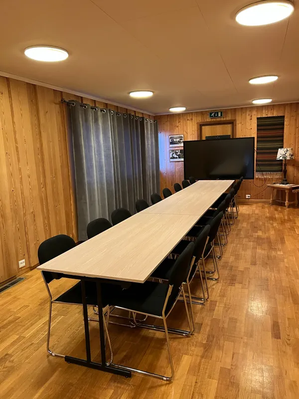 Møterommet med et langt bord, stoler langs begge sider og storskjerm på veggen.